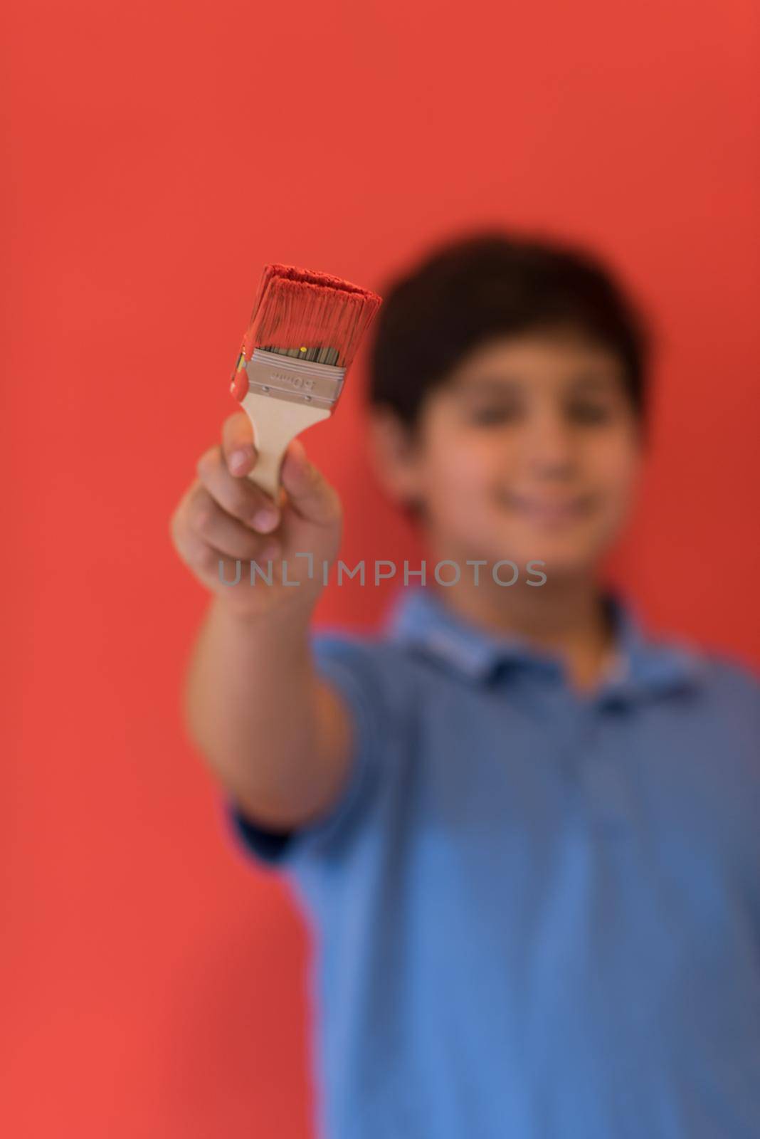 Portrait of a young boy painter with a brush in his hand in front of colored background