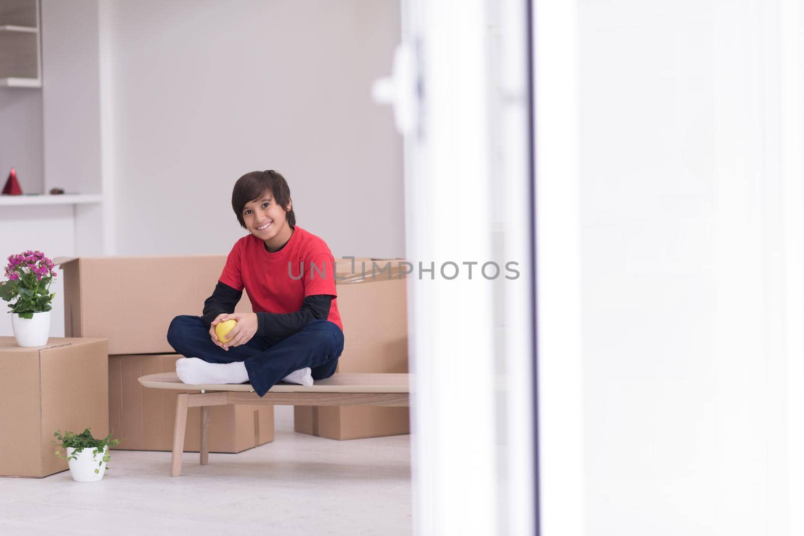 boy sitting on the table with cardboard boxes around him by dotshock