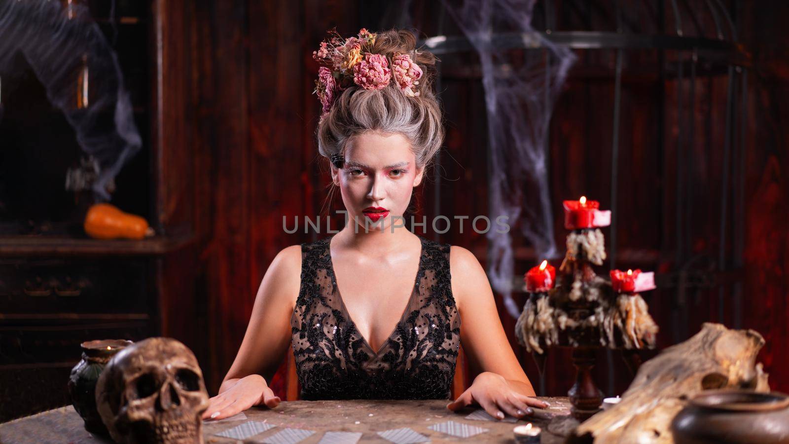 Portrait fortune teller woman reading future on magical cards. Magic and divination. Young beautiful enchanted female witch sitting on the table waiting your desire. Scary Halloween atmosphere