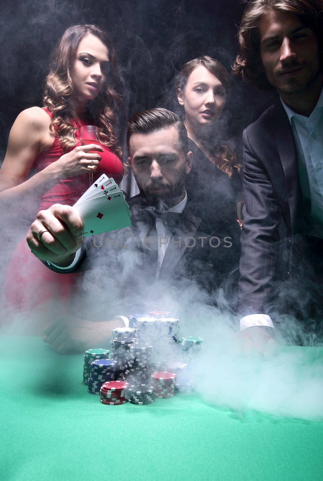 Young handsome man sitting behind poker table with card