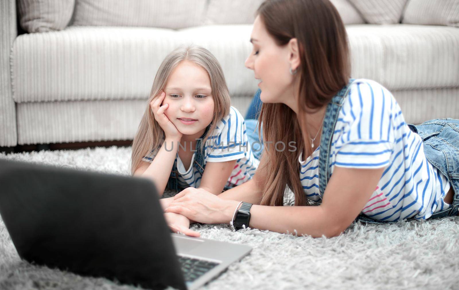 mother and daughter using a laptop in their home by asdf