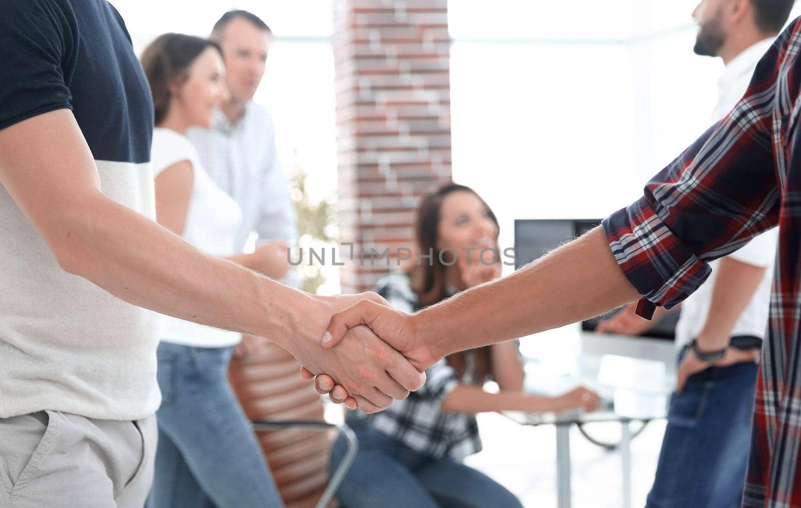 in the foreground handshake colleagues in creative office
