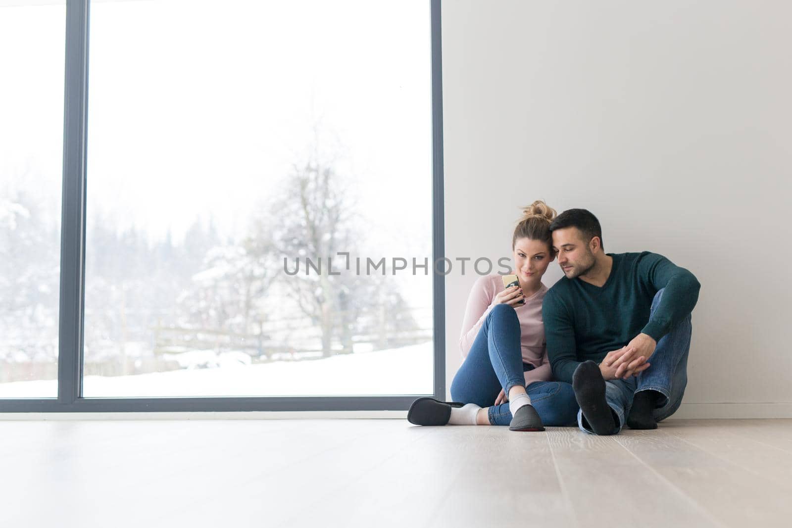 happy young couple sitting near window at home on cold winter day