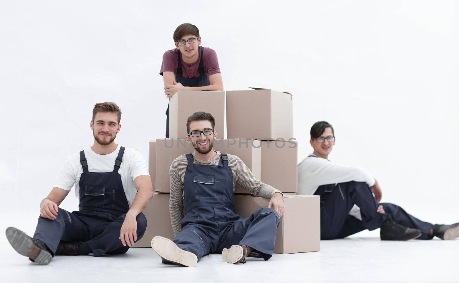 Smiling young delivery men holding stack of boxes. Isolated on w by asdf
