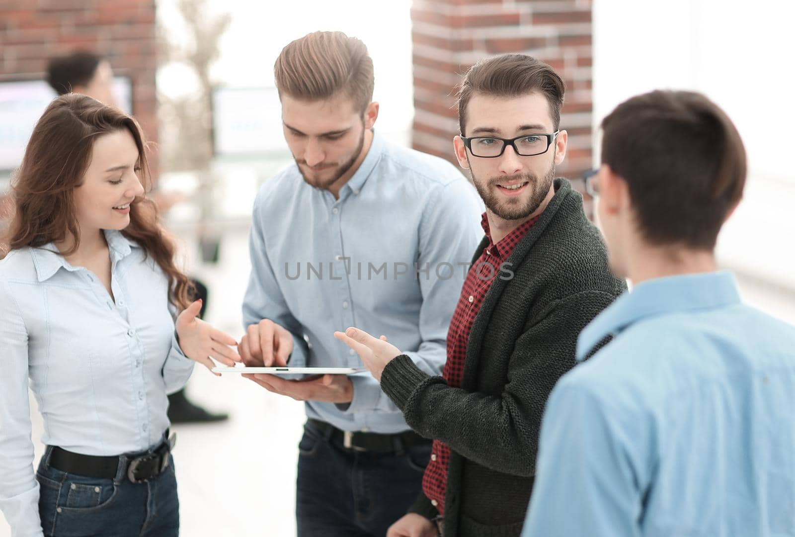 Beautiful business people are using gadget, talking and smiling while working in office.