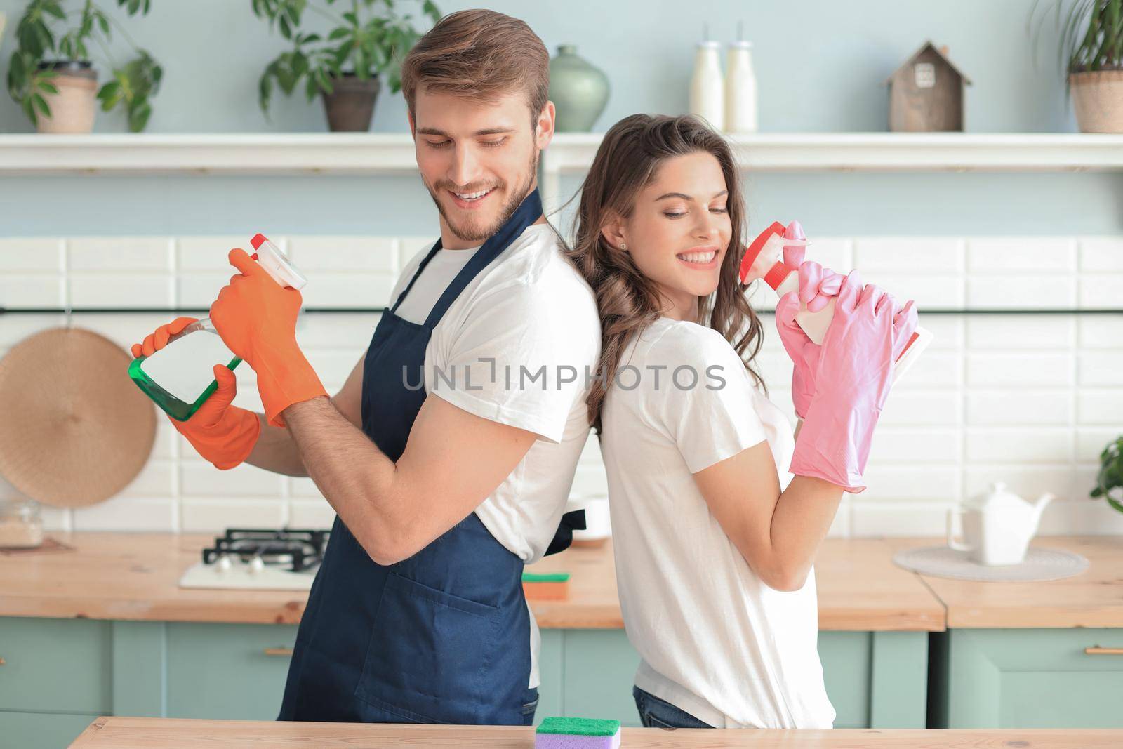 Young happy couple is having fun while doing cleaning at home