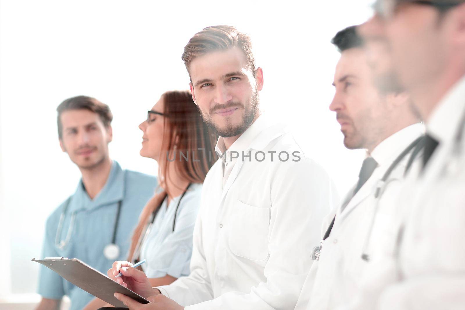 Close up of smiling doctor sitting with his team by asdf