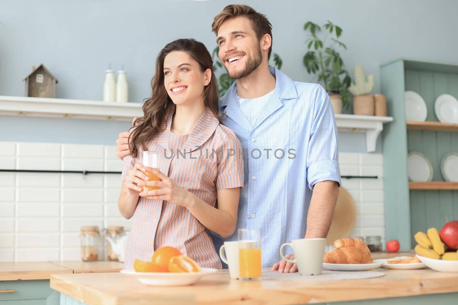 Beautiful couple hugging each other and looking away in kitchen in the morning