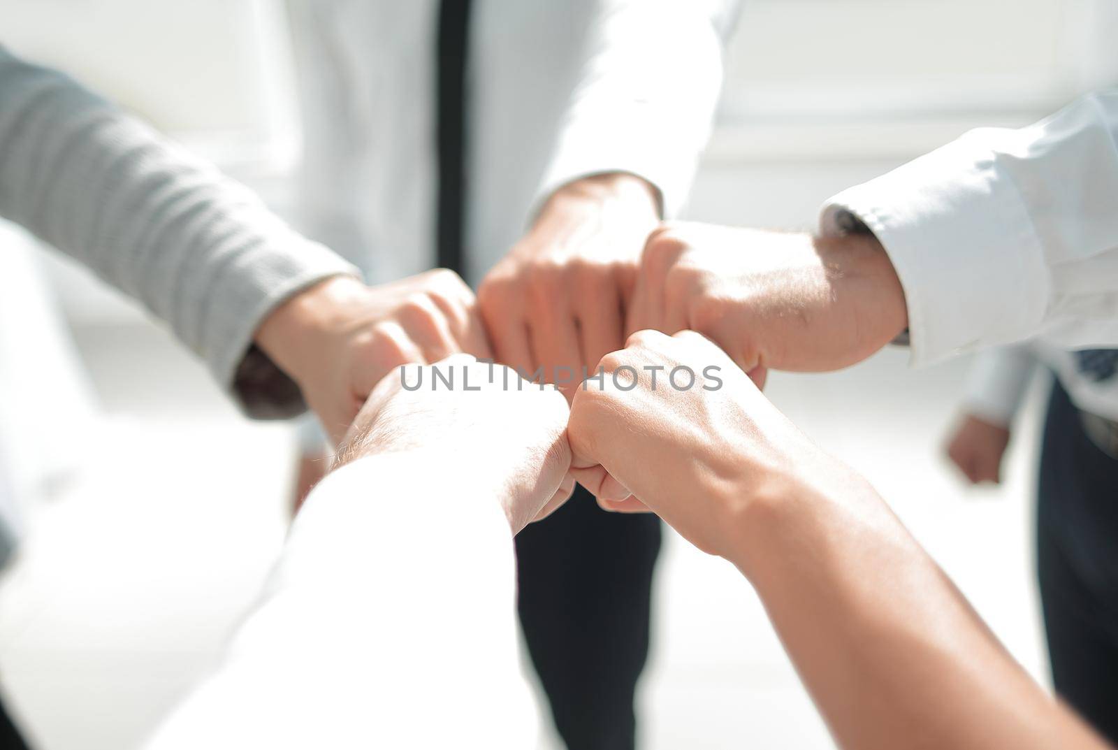 Close up of young businessman and businesswoman making a fist bump on building background