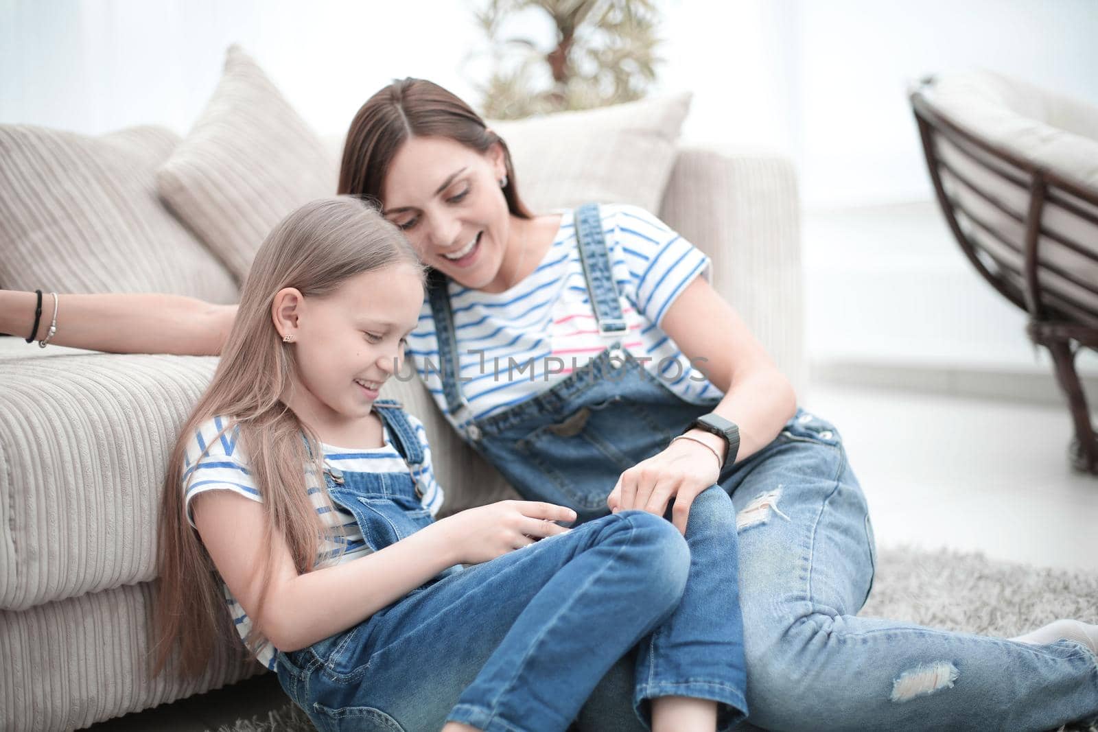 Mother with a little daughter using a smartphone sitting in the new living room by asdf