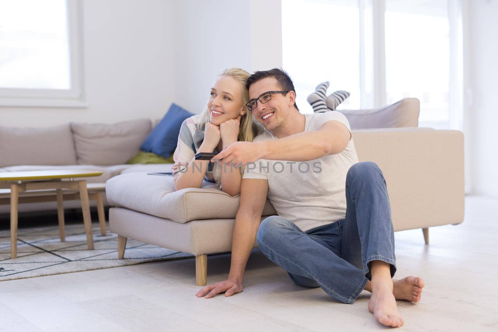 Young couple on the sofa watching television together in their luxury home