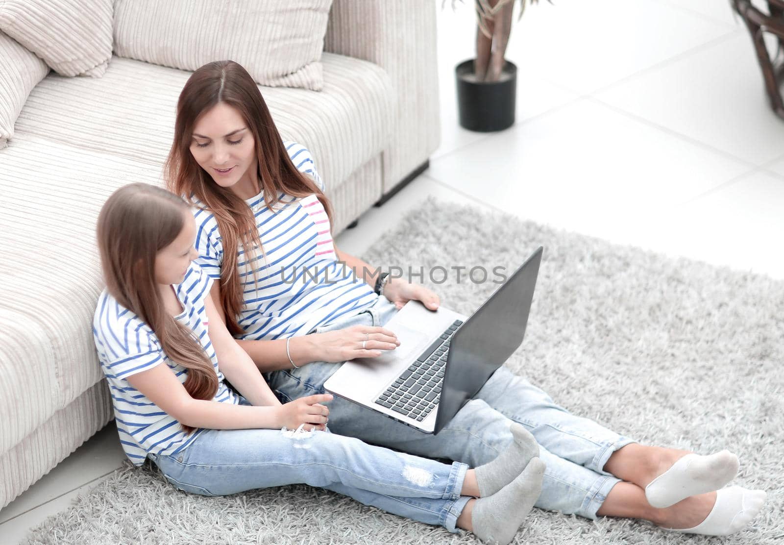 mother and daughter sitting on the floor in a cozy living room.photo with copy spac