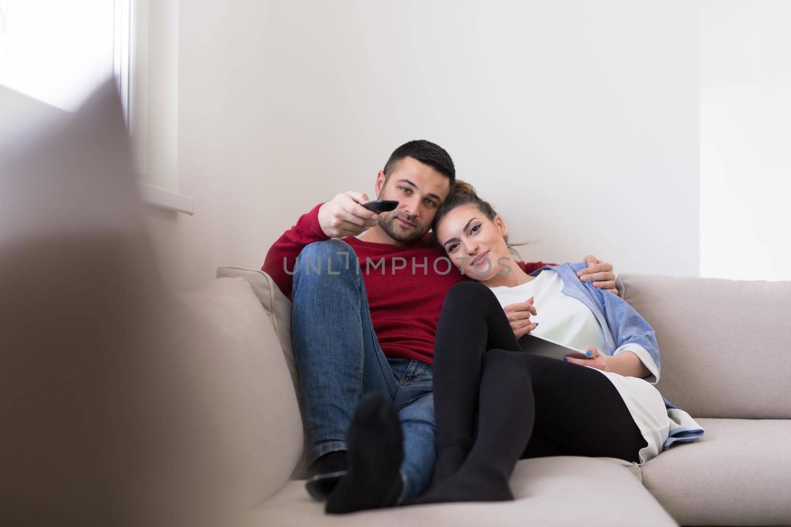 Young couple on the sofa watching television together in their luxury home