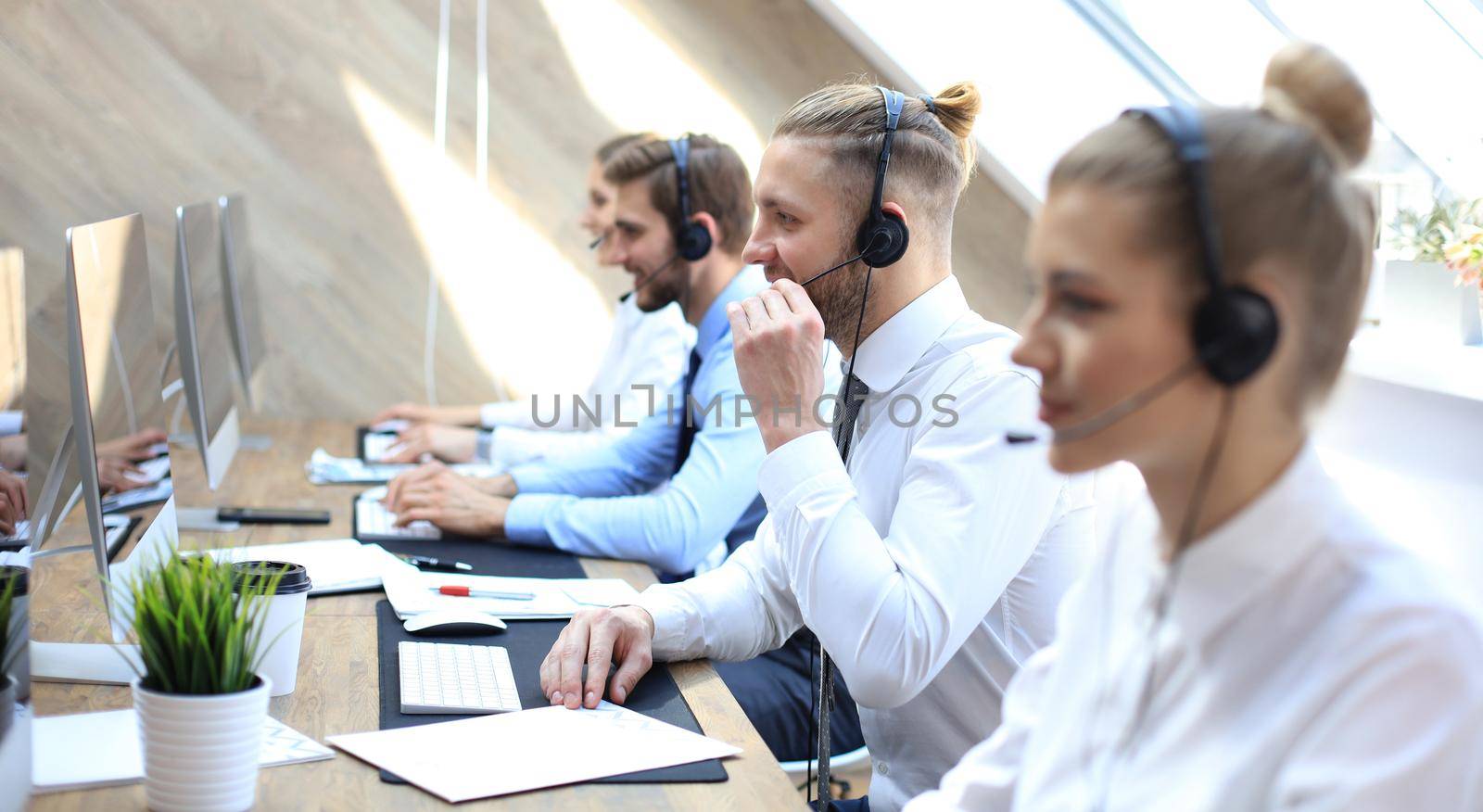 Portrait of call center worker accompanied by his team. Smiling customer support operator at work
