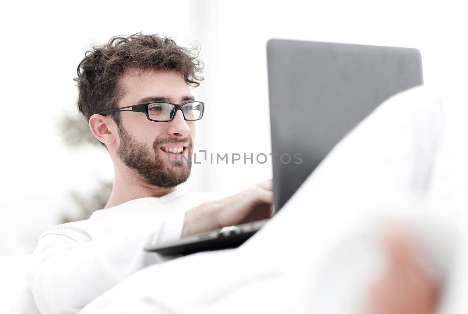 closeup.smiling man using laptop lying on bed
