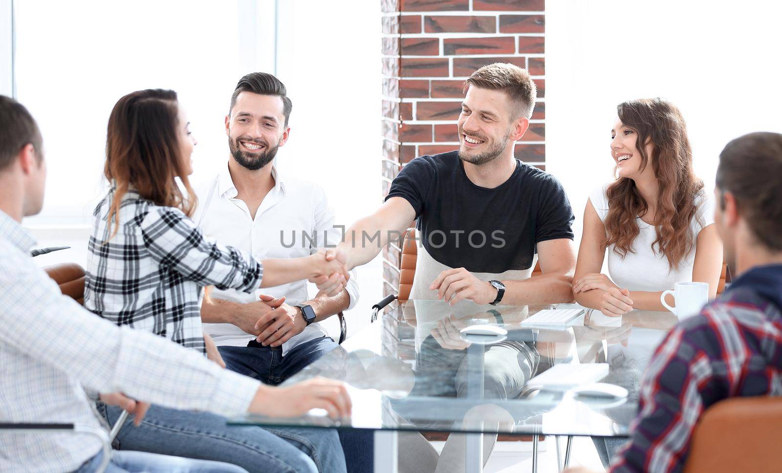 handshake colleagues at the workshop,sitting at a Desk