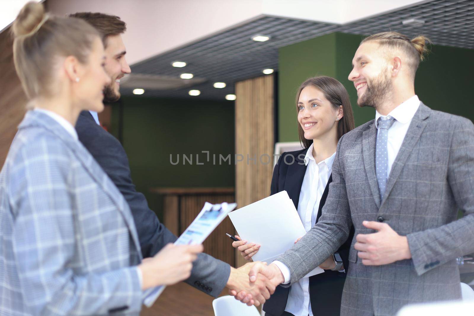 Business partners handshaking over business objects on workplace. by tsyhun