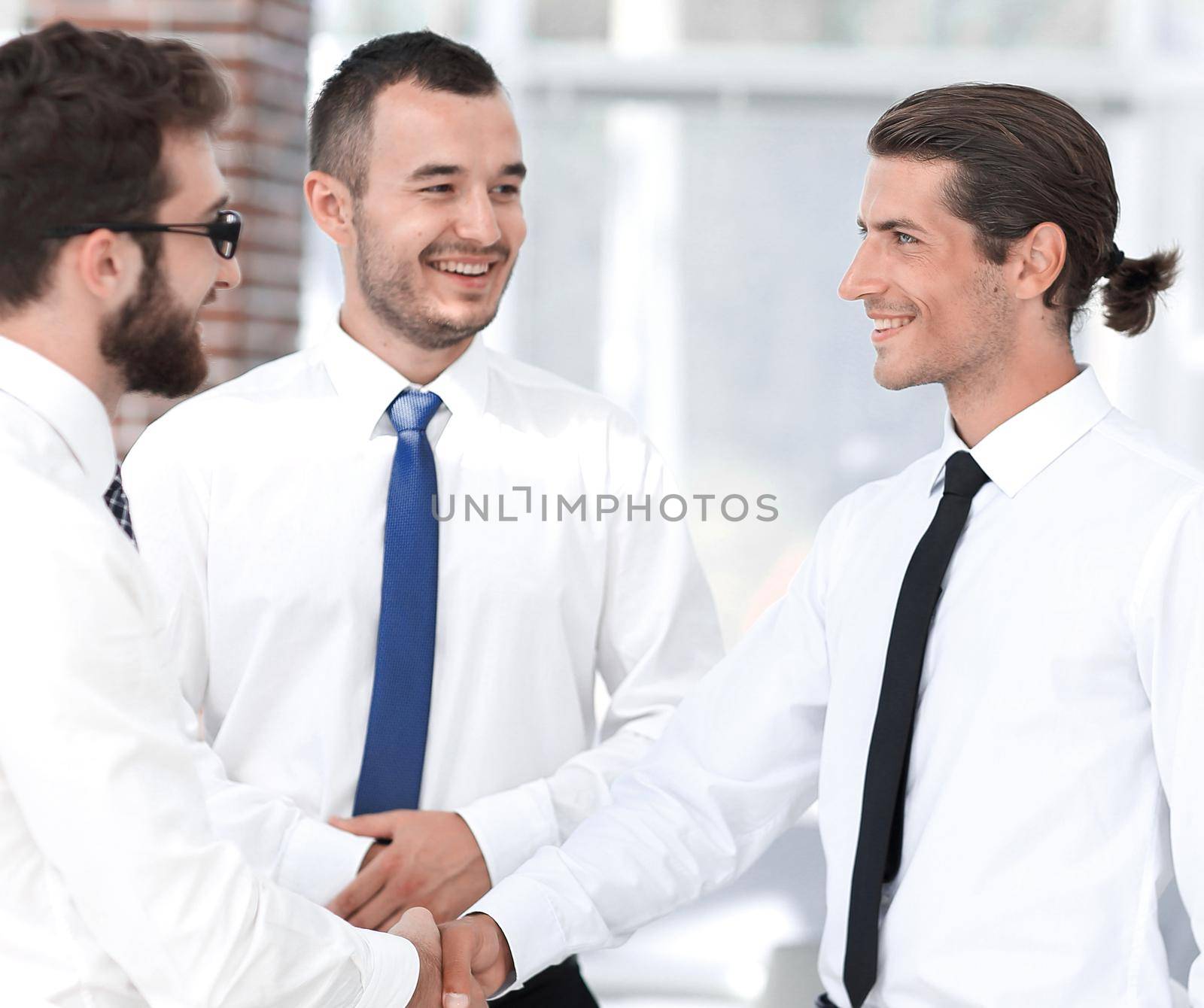 employees greet each other by shaking hands standing in the office