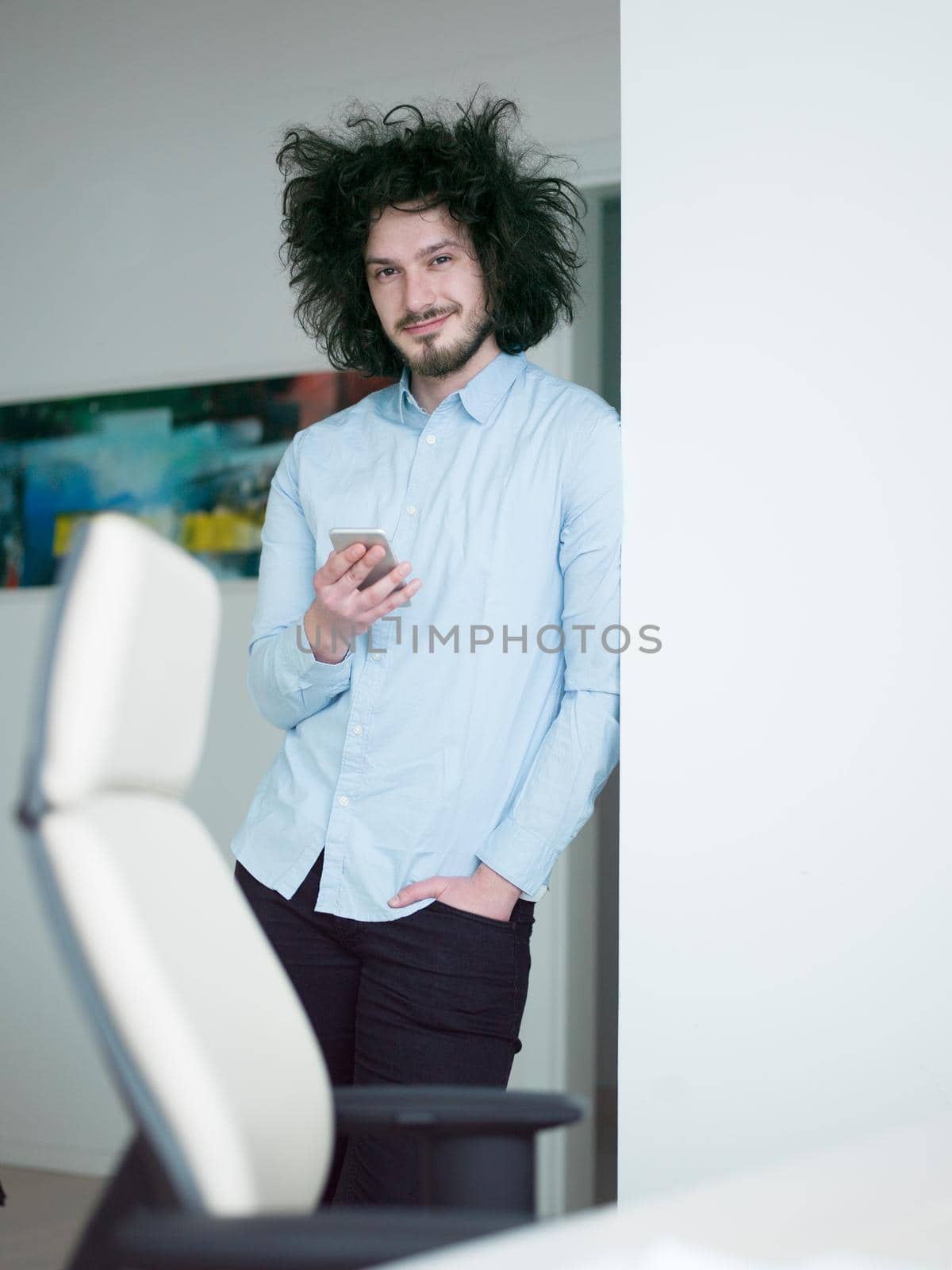 Handsome casual young man using a mobile phone in homemade office at luxury home