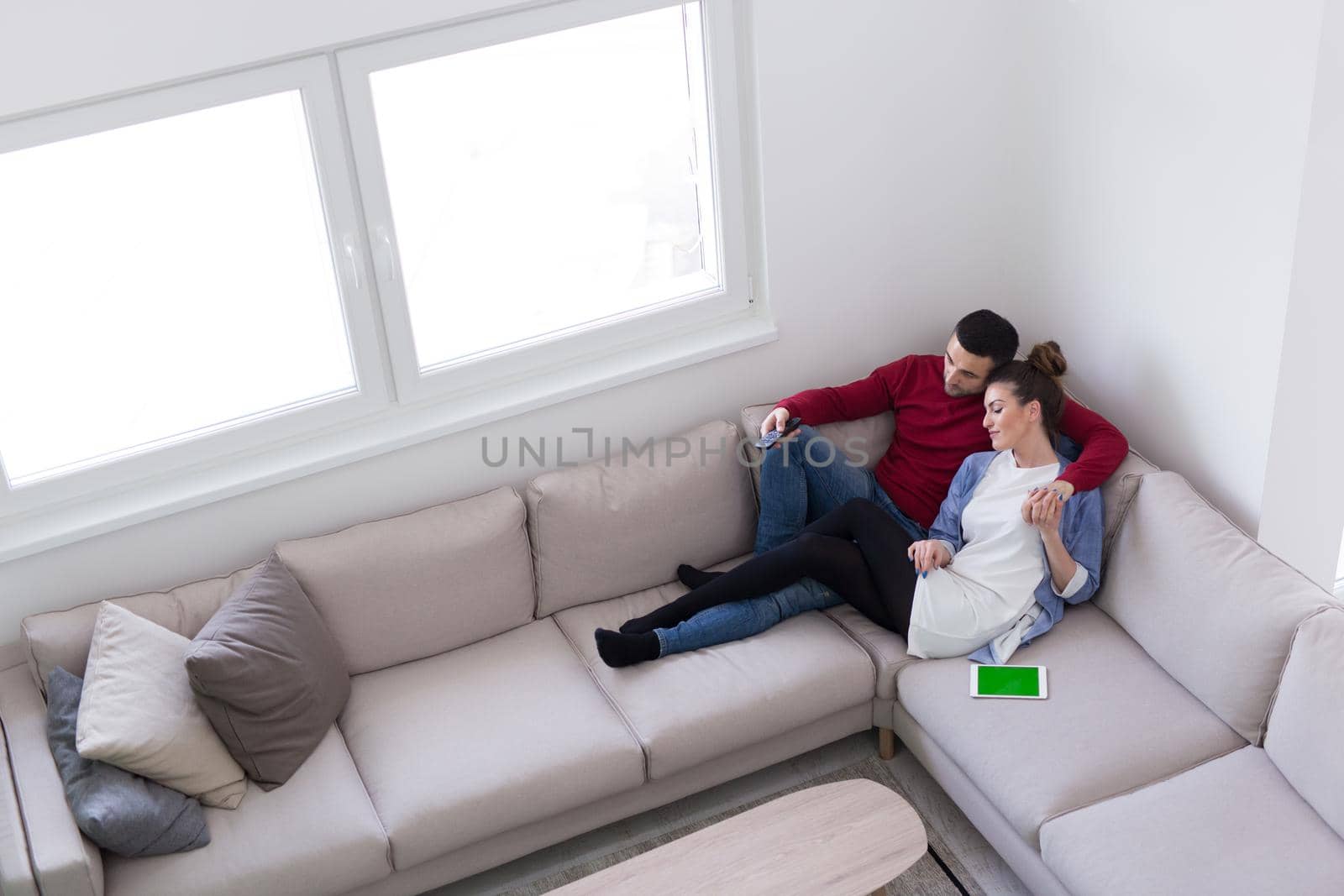 Young couple on the sofa watching television together in their luxury home