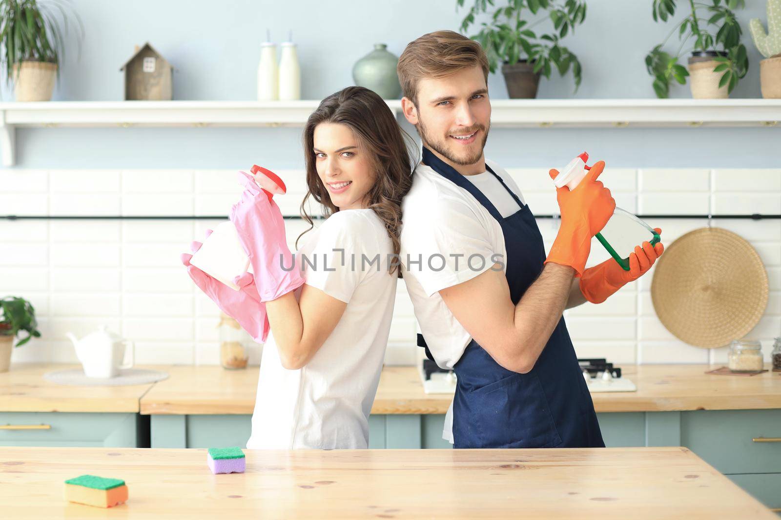 Young happy couple is having fun while doing cleaning at home. by tsyhun