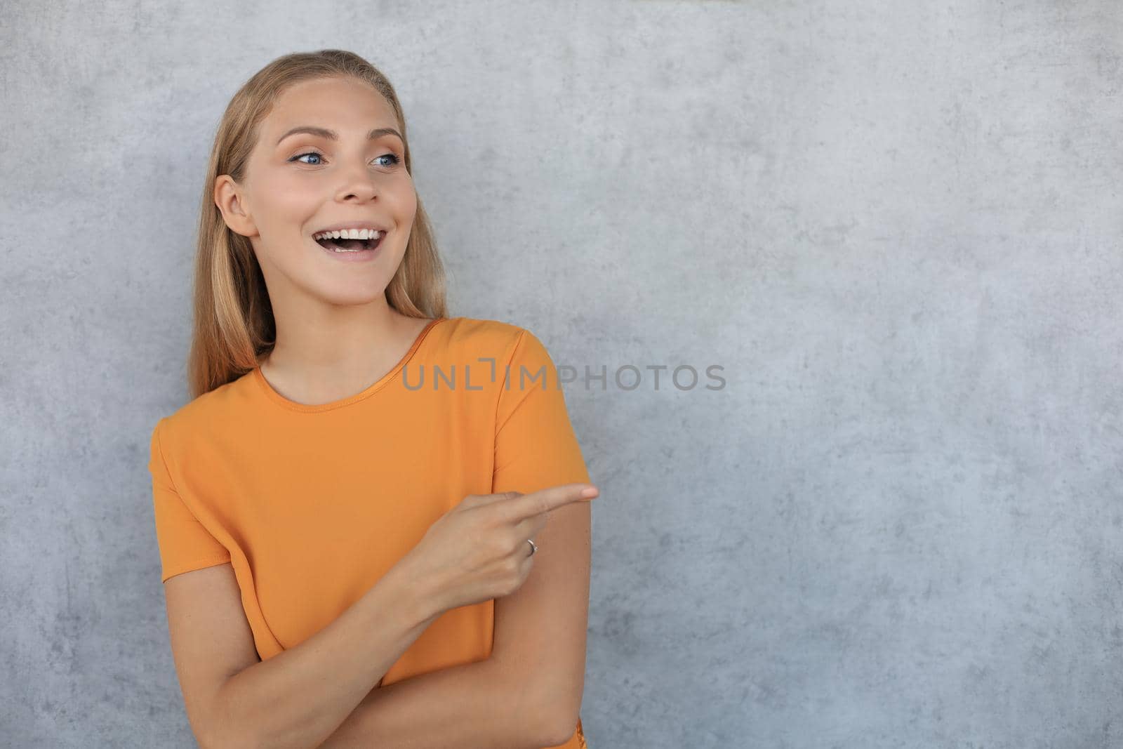 Portrait of smiling beautiful girl looking at camera over gray background.