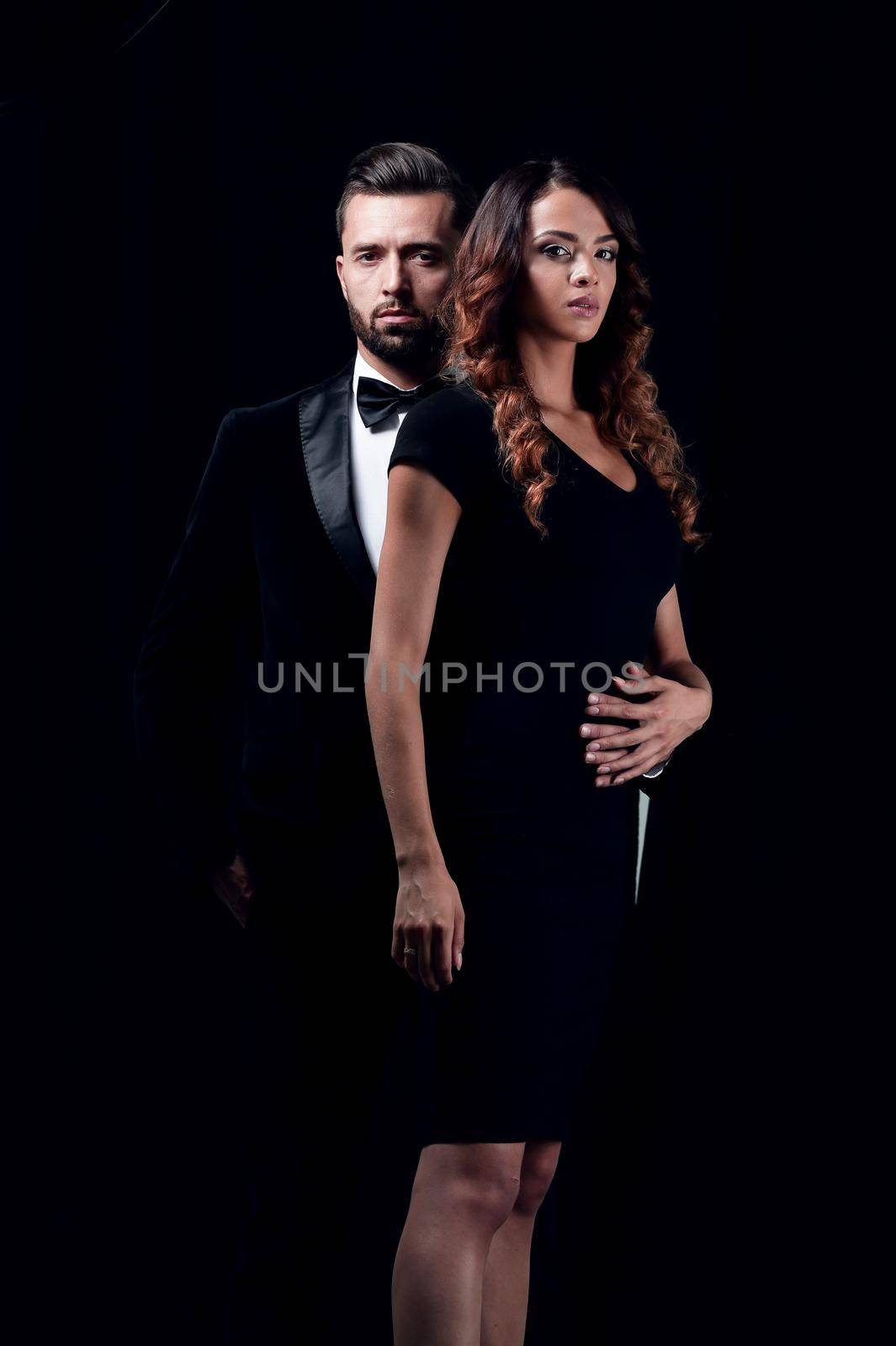 Young fashion man and woman on black background, looking at camera.