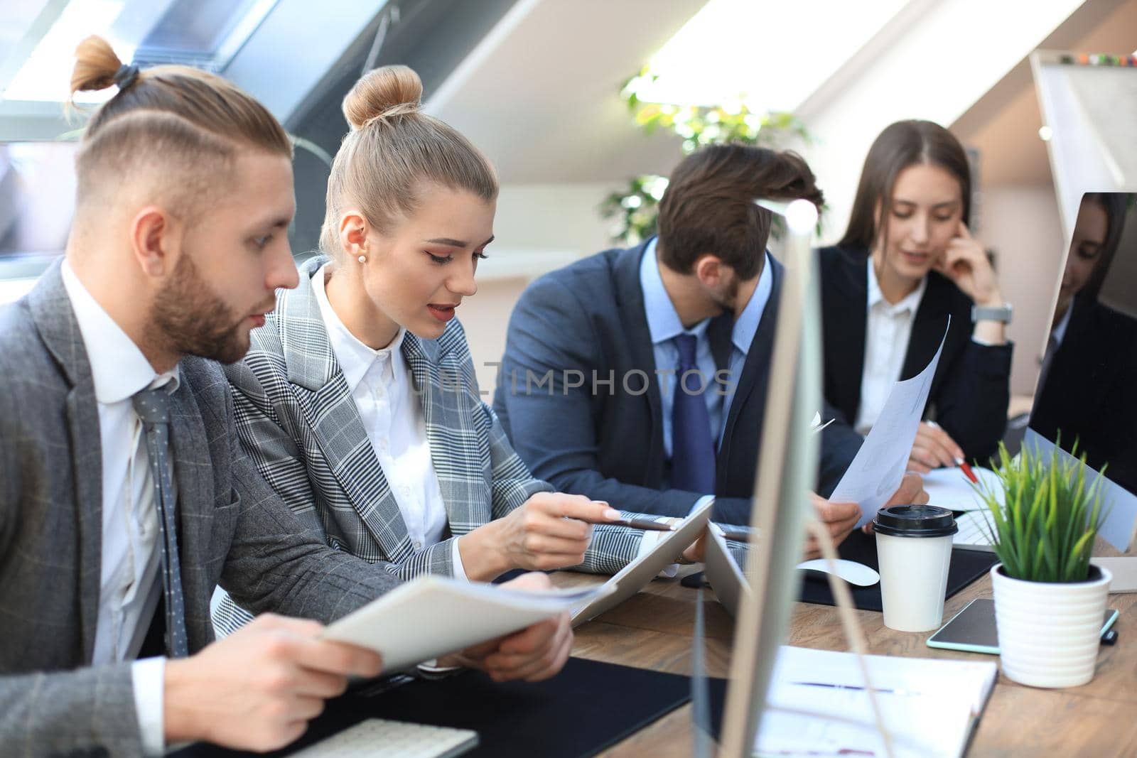 Group of young business people working, communicating while sitting at the office desk together with colleagues
