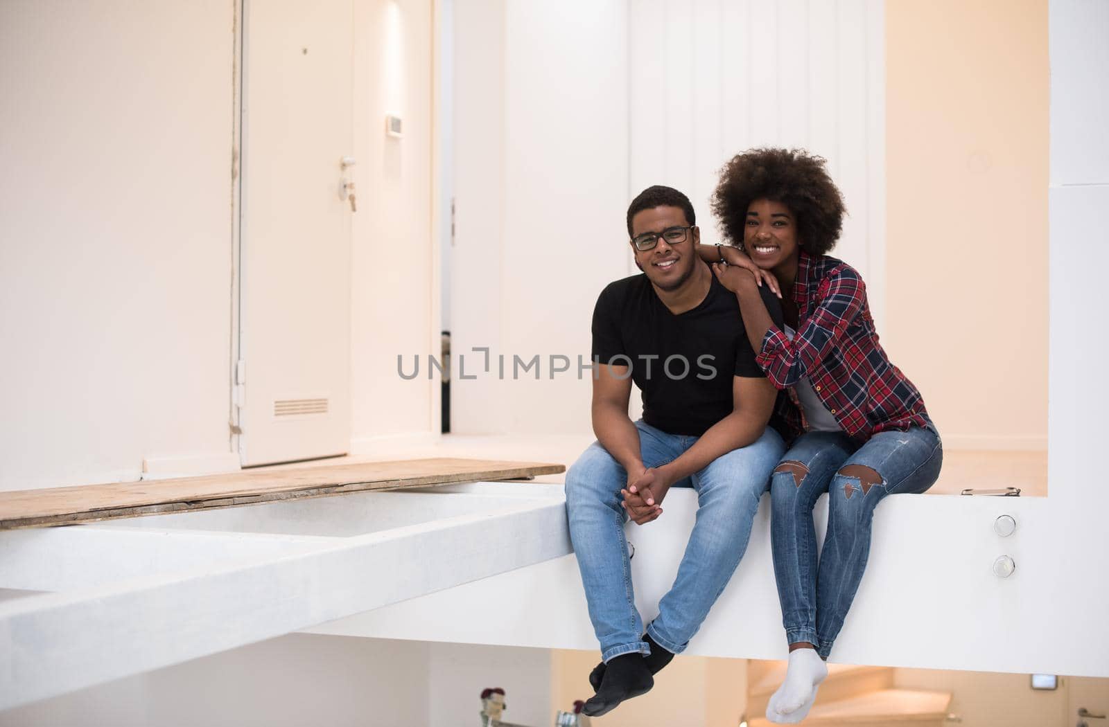 Happy young African American couple having break during moving to new house