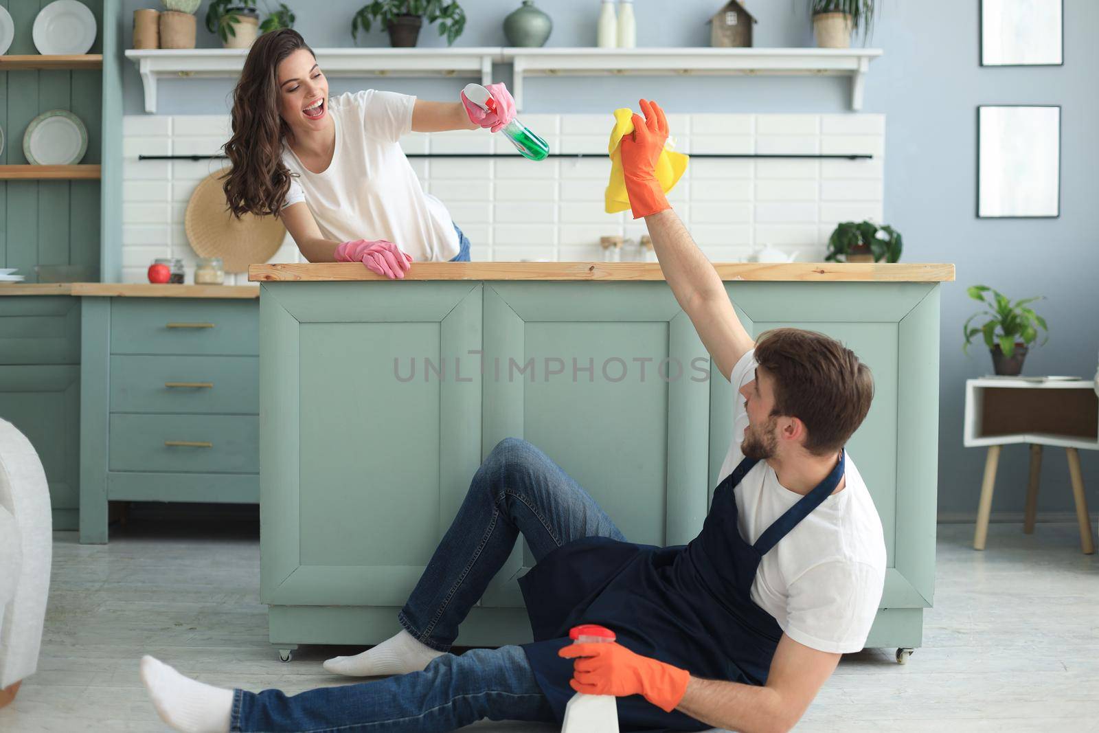 Young happy couple is having fun while doing cleaning at home. by tsyhun