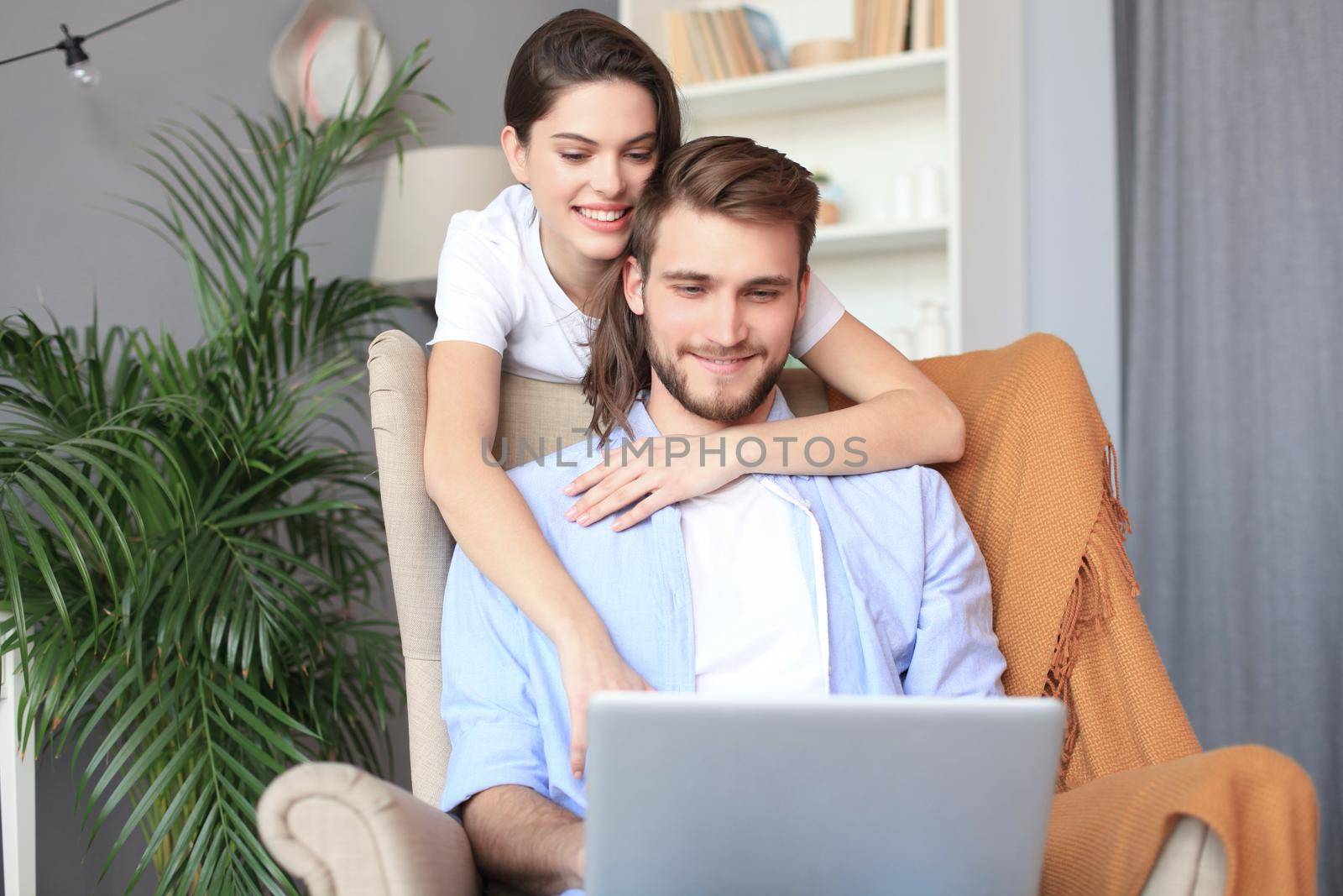 Young couple doing some online shopping at home, using a laptop on the sofa. by tsyhun