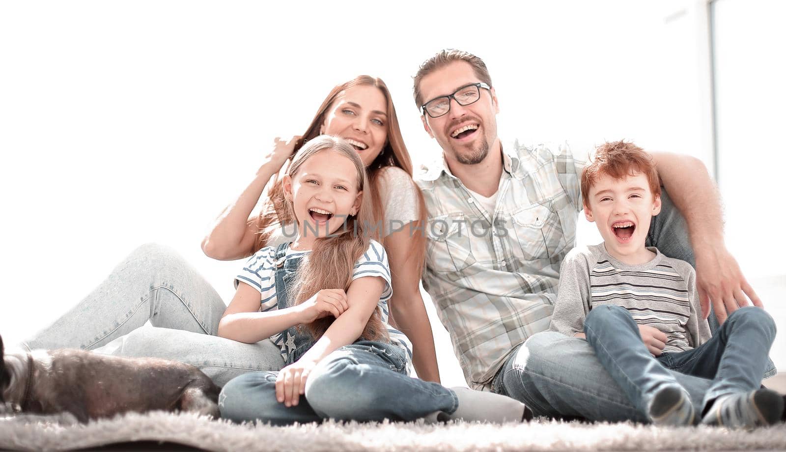 cheerful family sitting on the carpet in the new living room.the concept of happiness