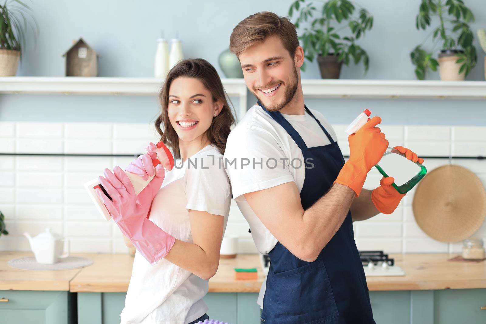 Young happy couple is having fun while doing cleaning at home. by tsyhun
