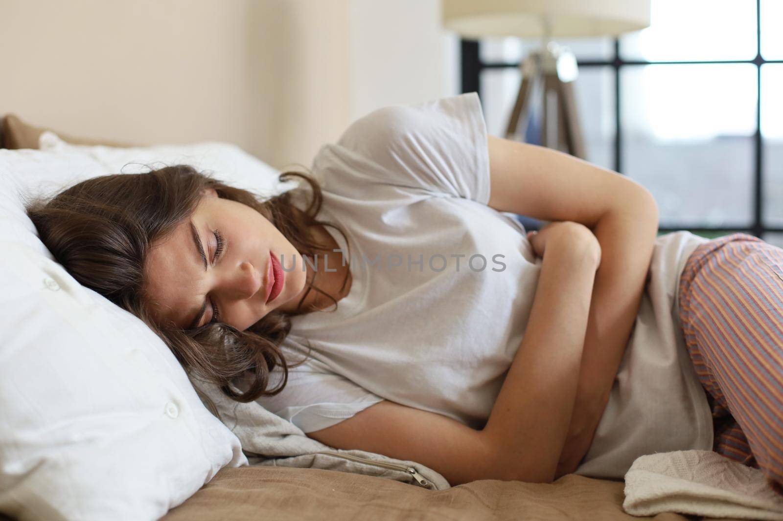 Sick woman on bed concept of stomachache