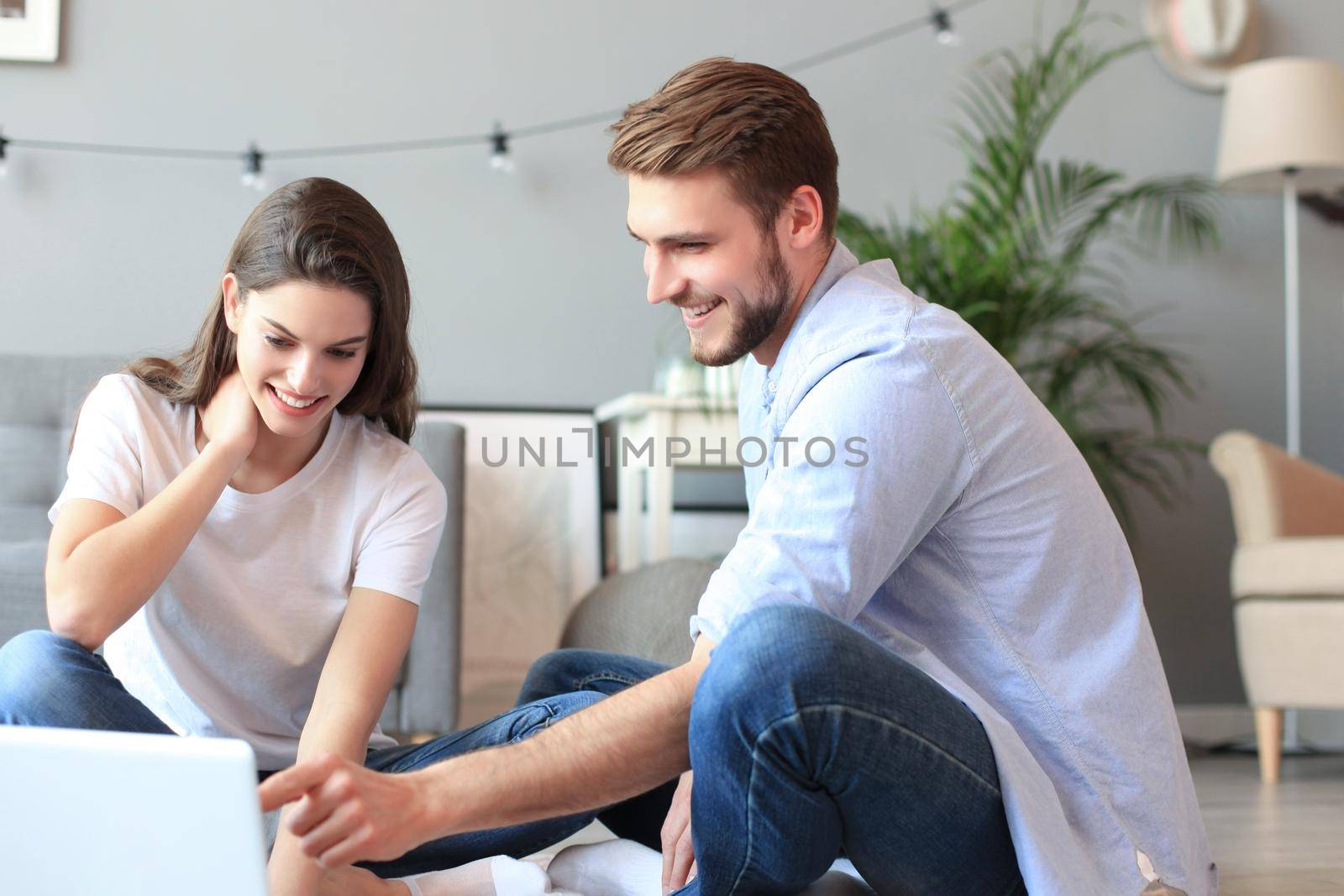 Young couple doing some online shopping at home, using a laptop on floor. by tsyhun