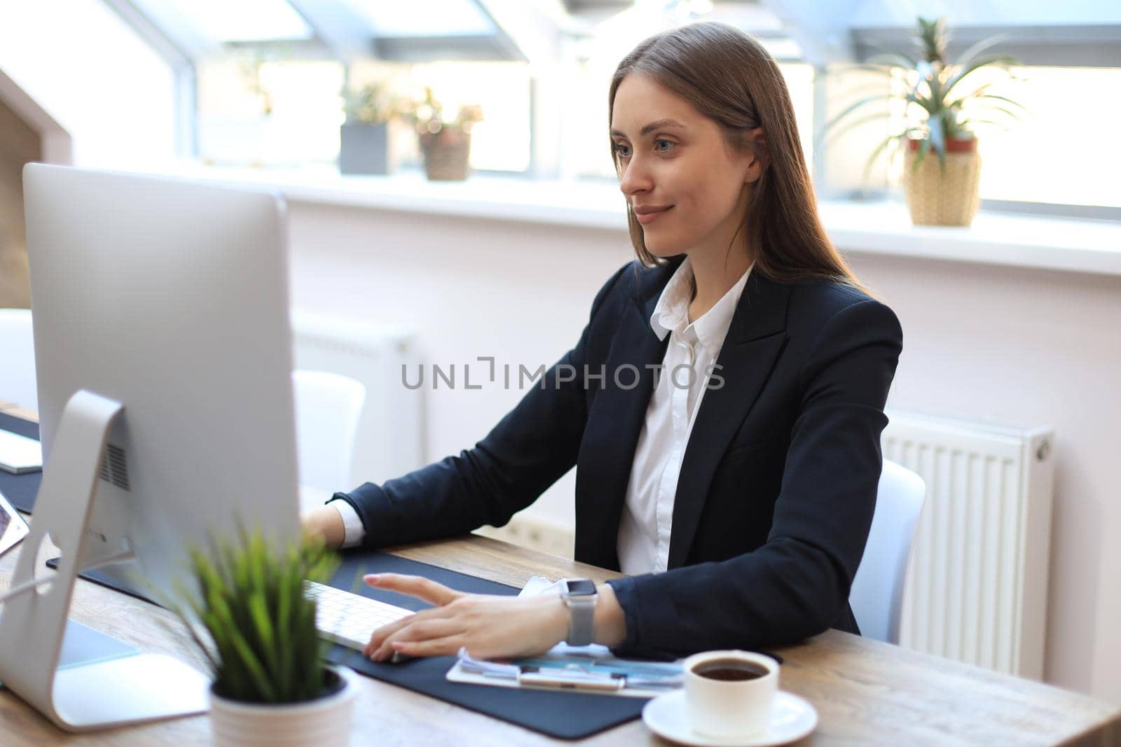 Portrait of a young blond business woman using computer at office