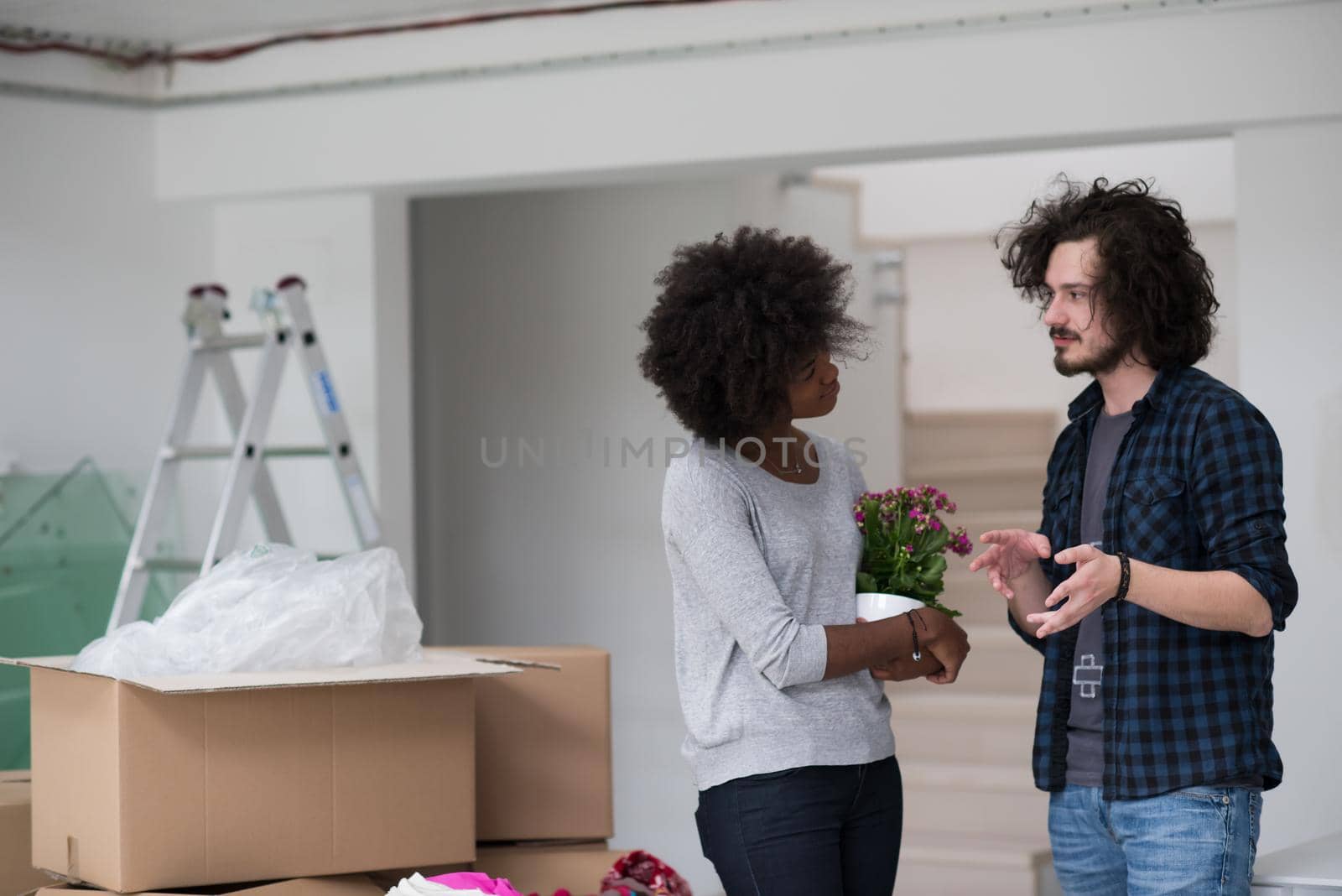 Happy young multiethnic couple unpacking or packing boxes and moving into a new home