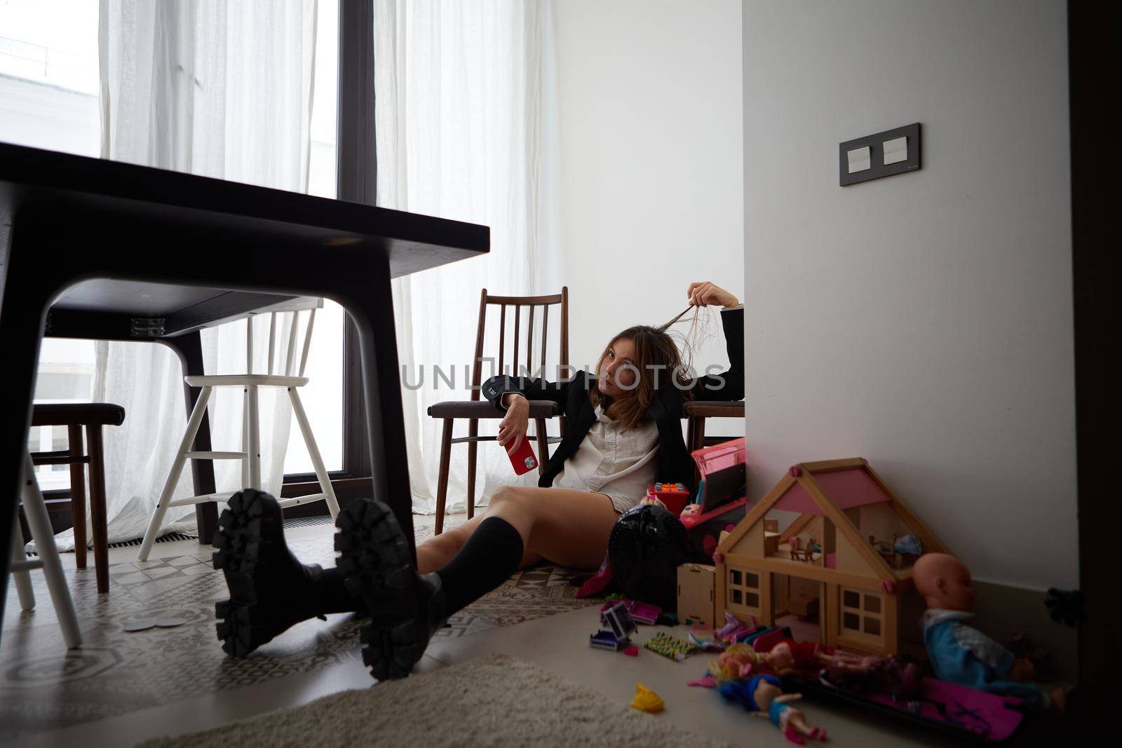 Childish woman sitting near doll house on floor by Demkat