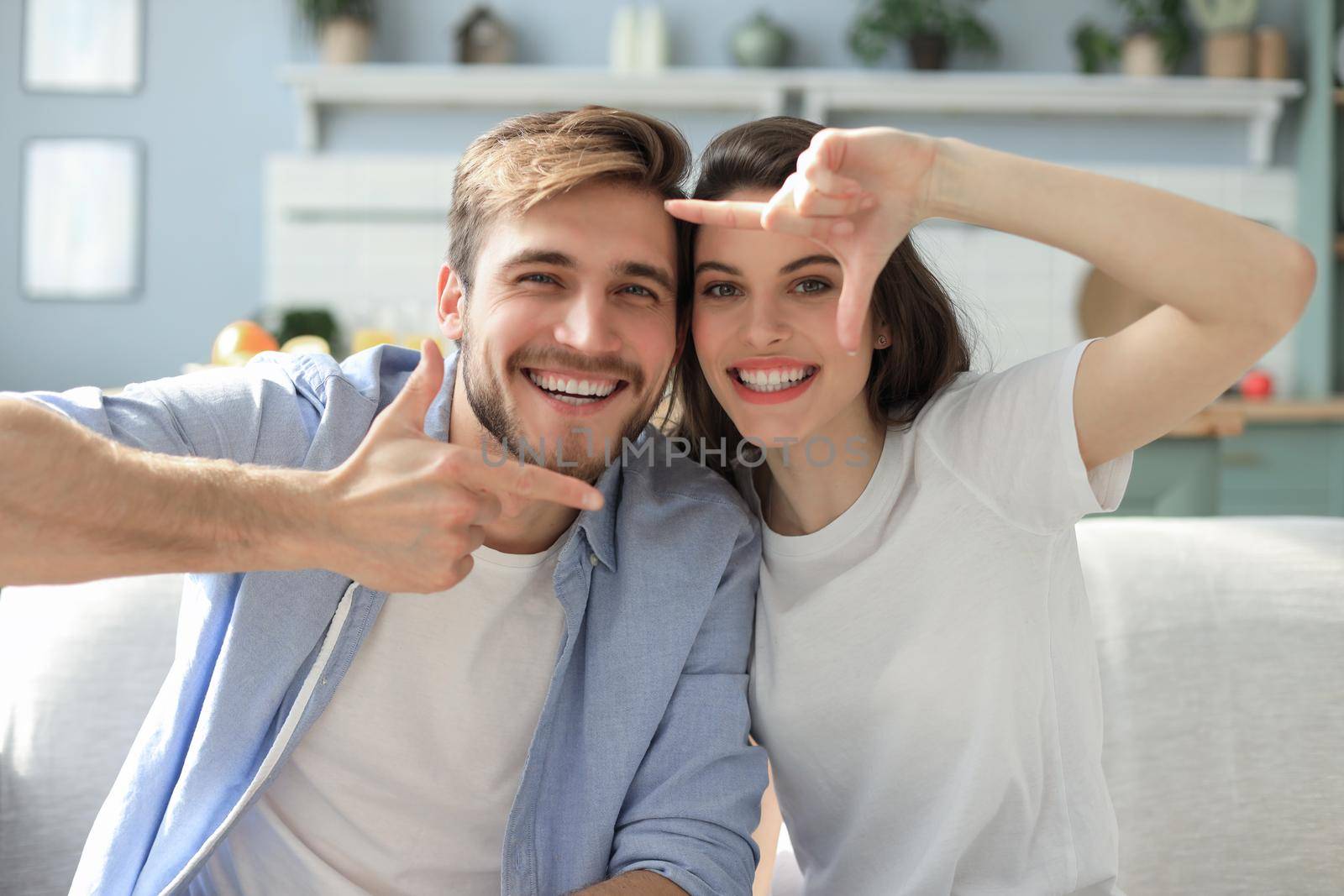 Romantic beautiful smiling couple making selfie for fun, at home sitting on the sofa