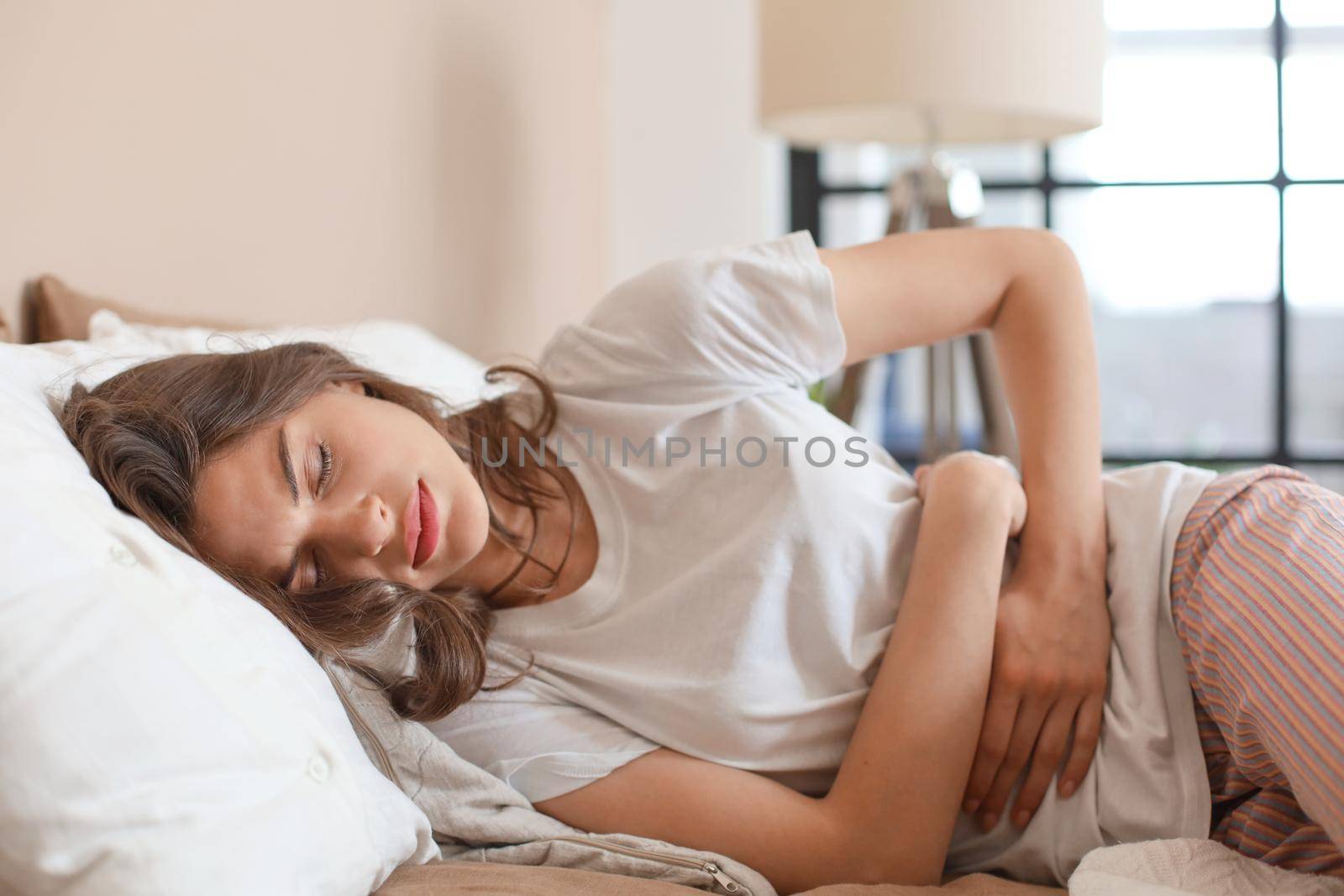 Sick woman on bed concept of stomachache