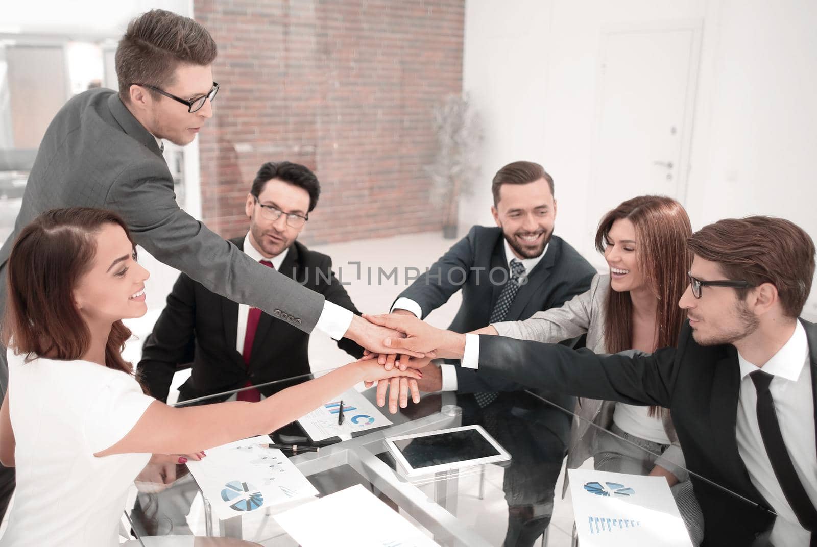 group of employees folded their hands together over the Desk. concept of success