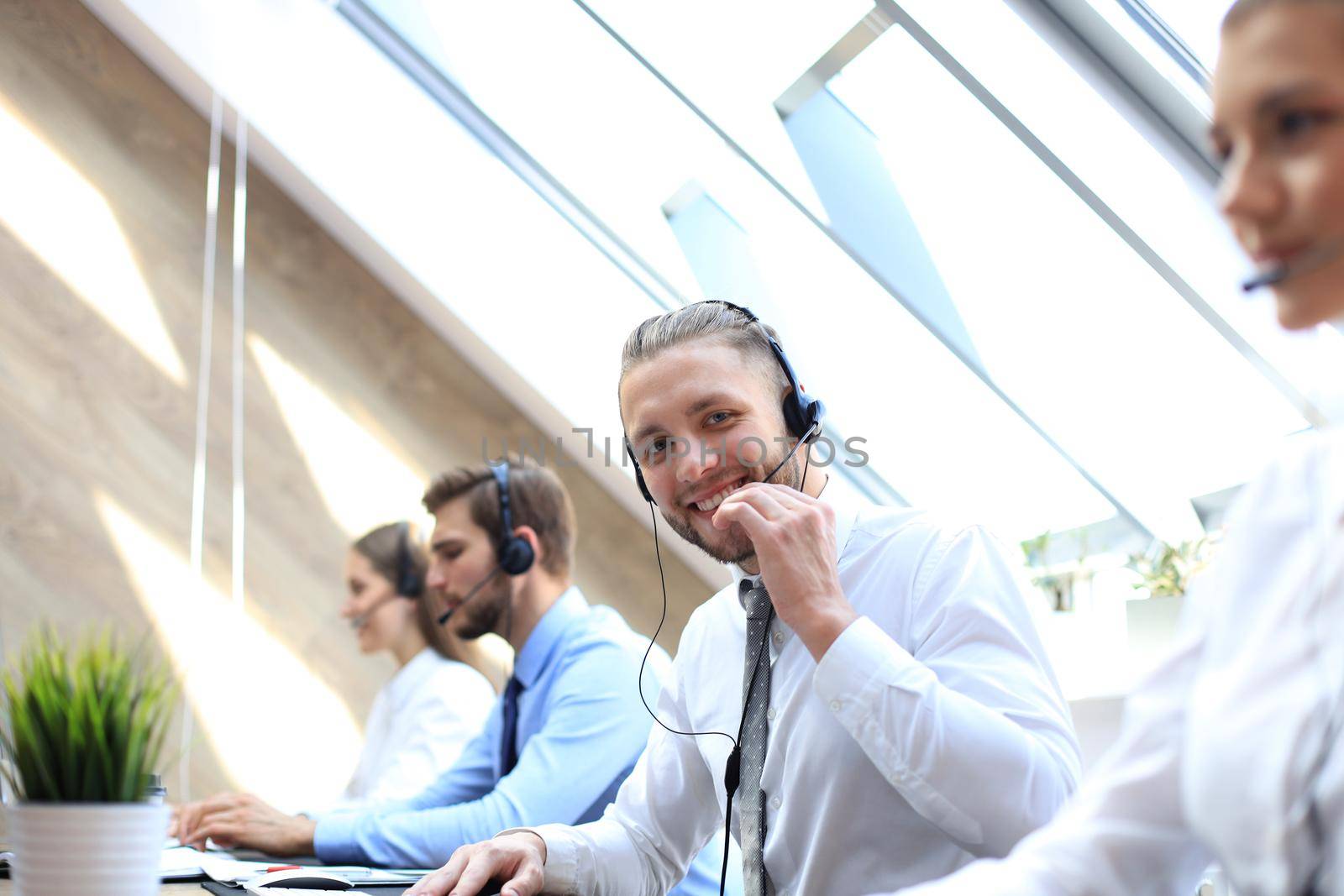 Portrait of call center worker accompanied by his team. Smiling customer support operator at work