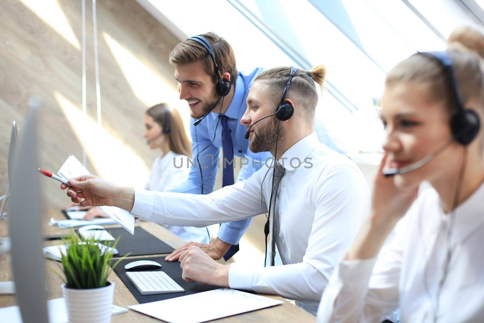 Phone operator working at call centre office helping his colleague