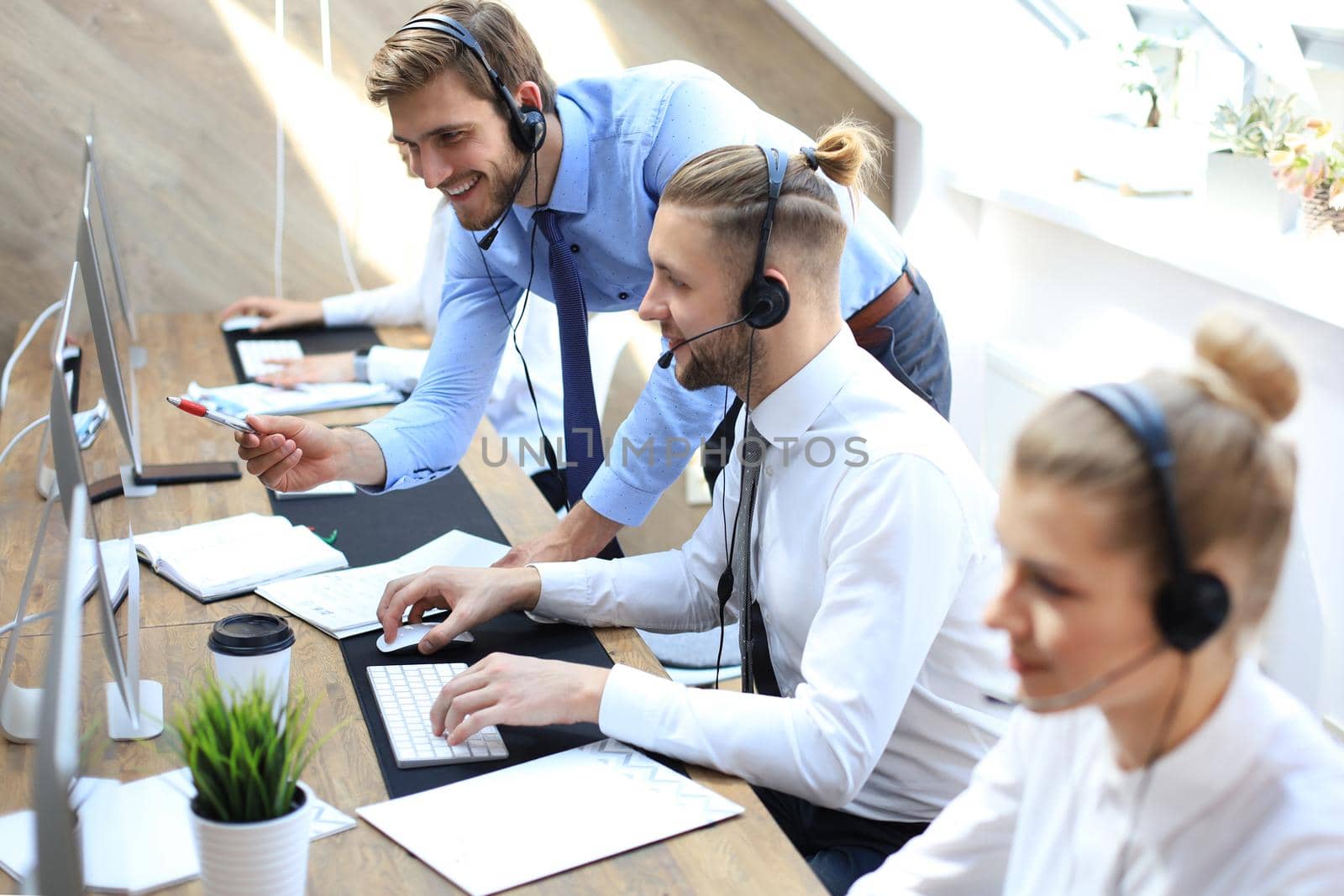 Phone operator working at call centre office helping his colleague