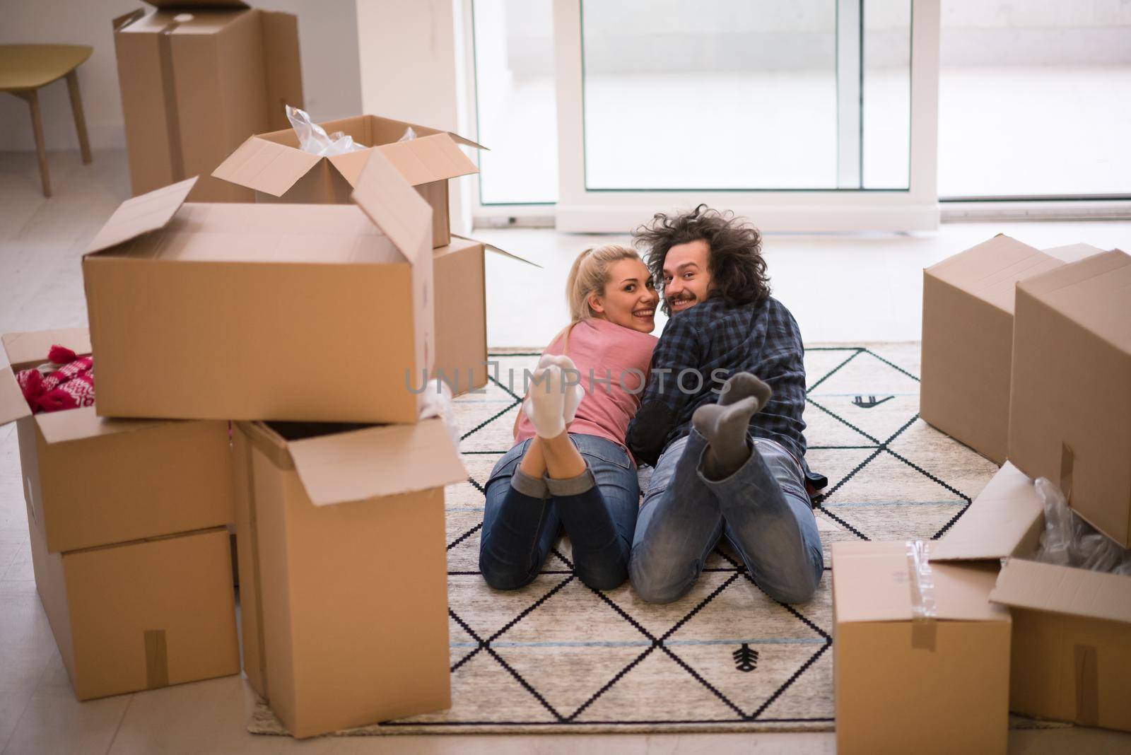 Young couple in love moving in a new flat, lying on the floor and surfing the web on a tablet computer in search of new redecoration ideas
