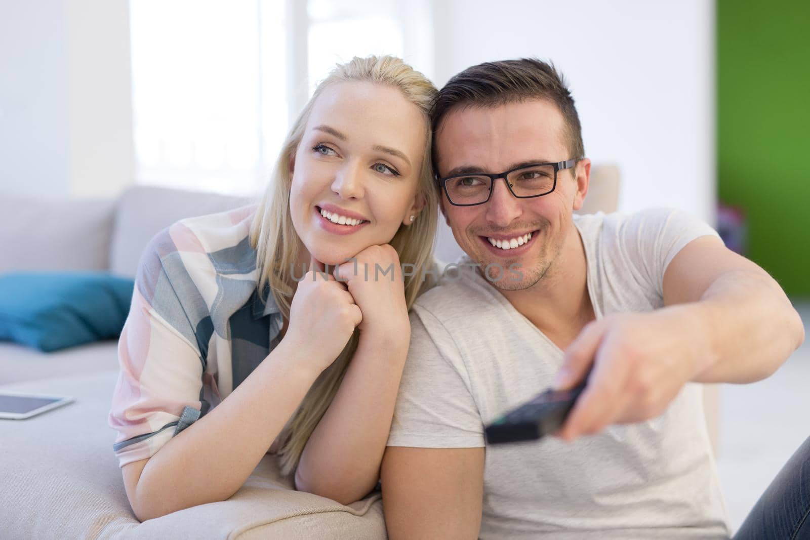 Young couple on the sofa watching television together in their luxury home