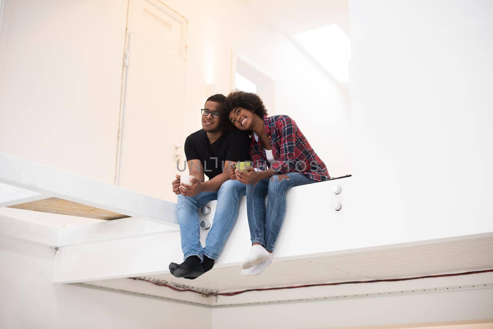 Happy young African American couple having break during moving to new house