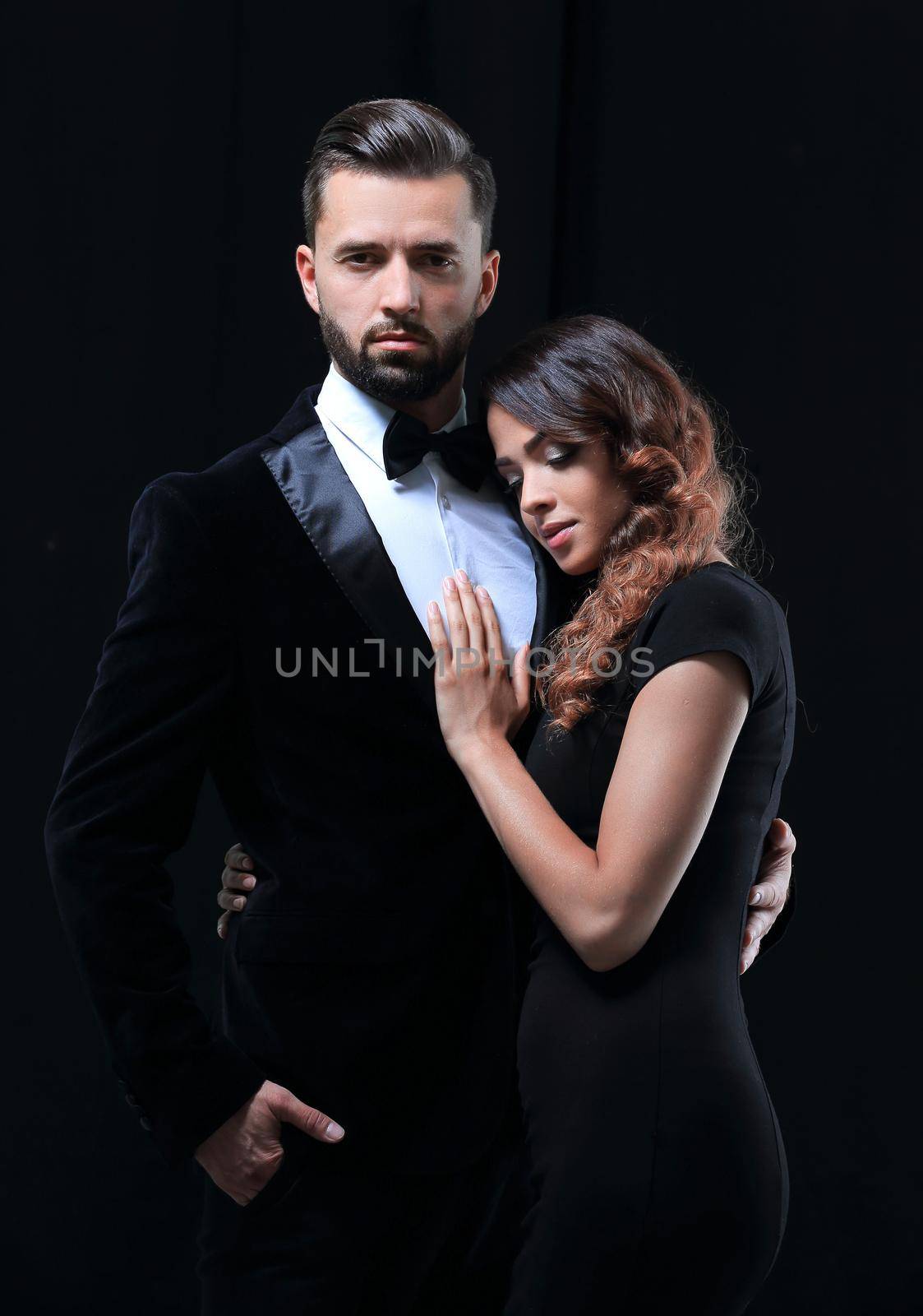 Portrait of young couple in love posing at studio dressed in classic clothes