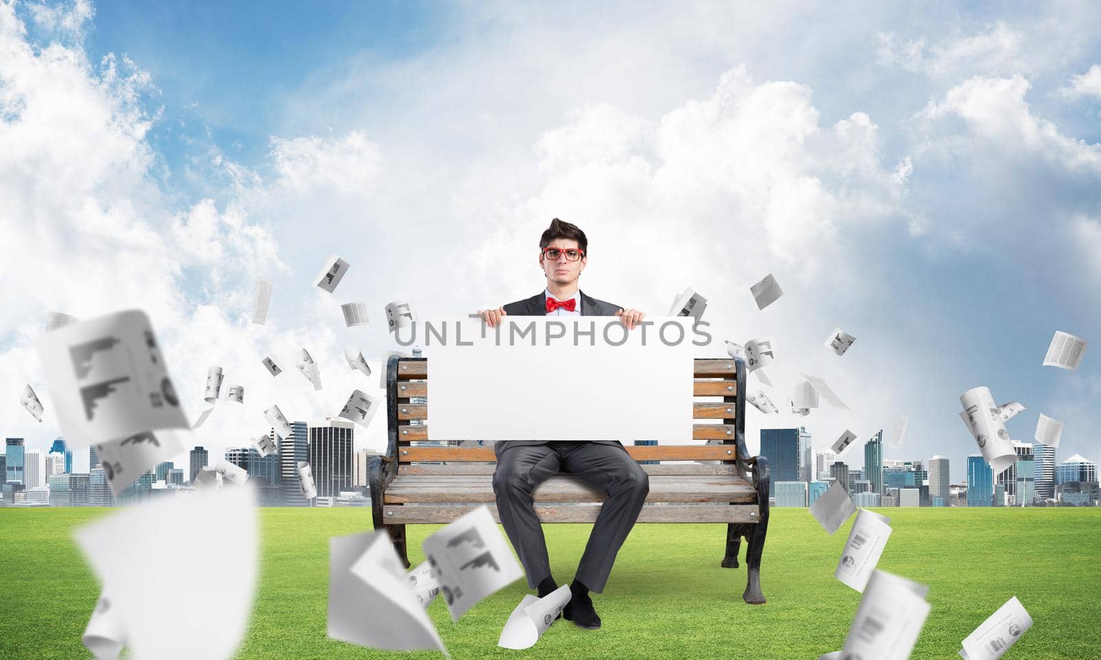 young businessman sits on a bench with an empty banner. around in the chaos flying documents