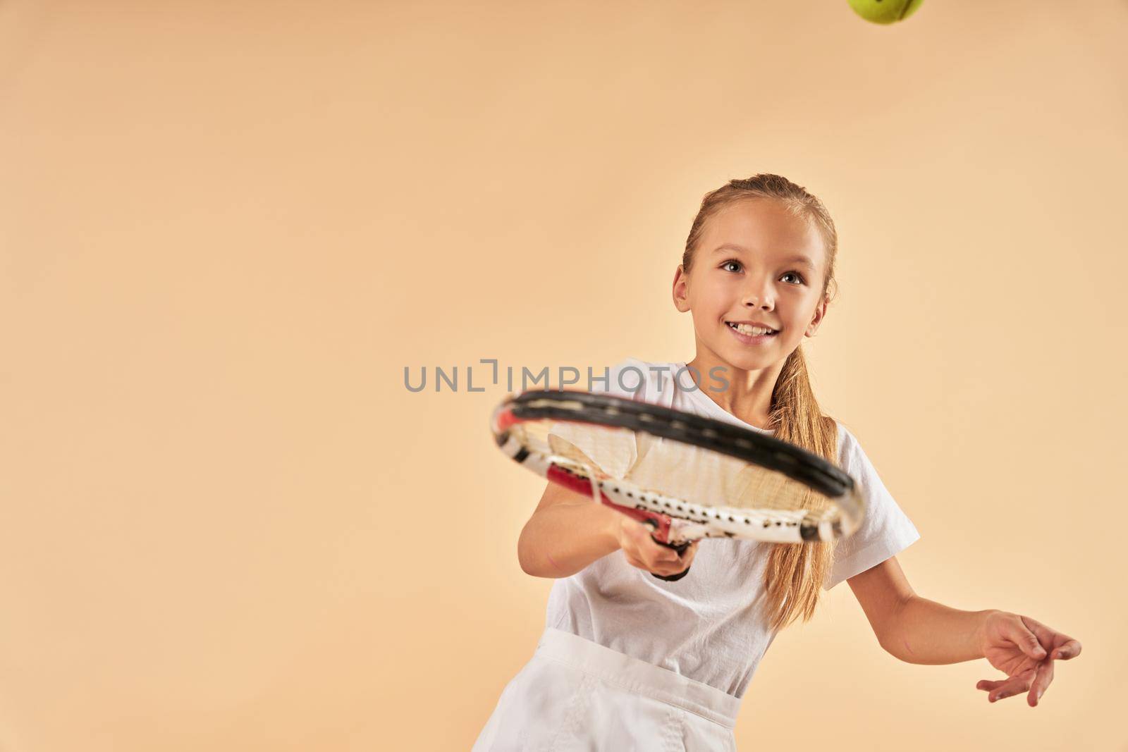 Cute female child playing tennis and smiling by friendsstock